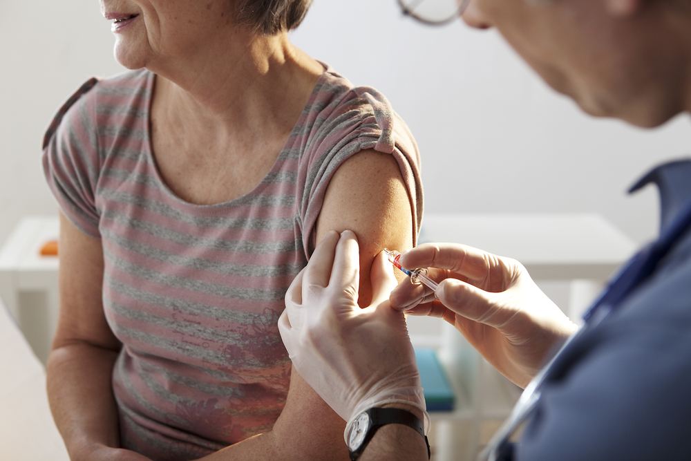 A nurse giving a vaccination in a patient&rsquo;s upper arm